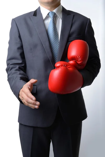 Uomo d'affari togliti i guanti da boxe per offrire una stretta di mano su bianco — Foto Stock