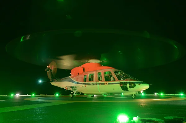 La noche del helicóptero aterrizando en la plataforma petrolífera en alta mar — Foto de Stock