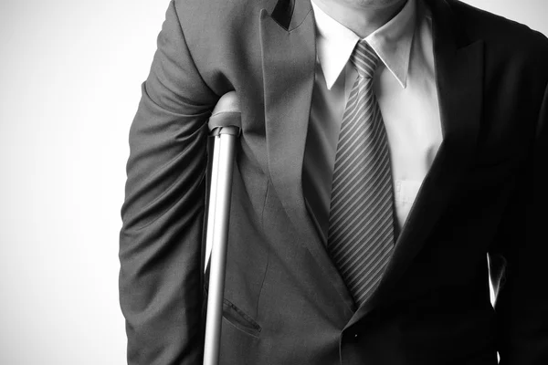 Skadade affärsman med kryckor, försäkring koncept Stockfoto
