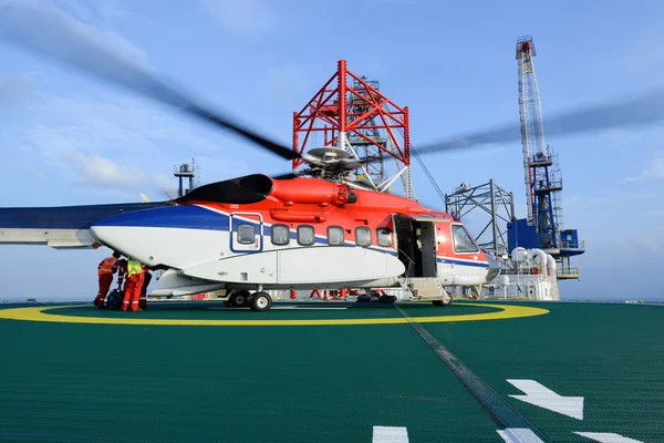 Arbetaren lastar bagage av passagerare till helikopter på olja Royaltyfria Stockbilder