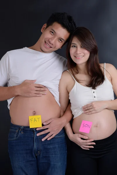 Buik van zwangere vrouw en man met grappige inscriptie "vet" — Stockfoto