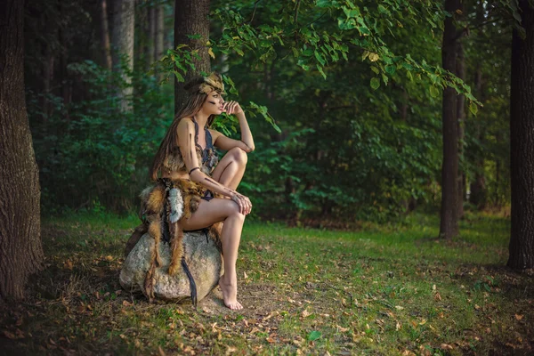 Elegante y hermosa amazona joven sentada en una roca en el bosque — Foto de Stock