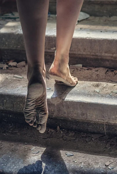 Menina descalça sobe as escadas de uma casa arruinada — Fotografia de Stock