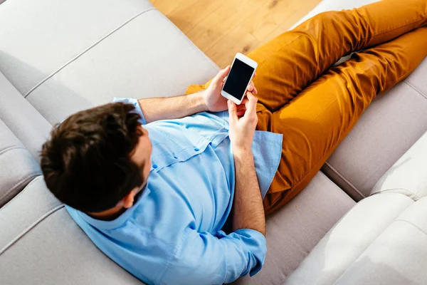 Mann benutzt sein Handy auf dem Sofa — Stockfoto