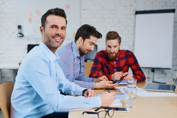 Heureux homme d'affaires assis au bureau — Photo