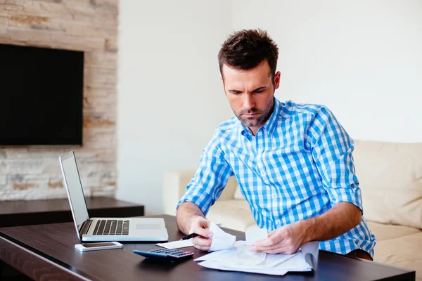 Man at home holding bills — Stock Photo, Image