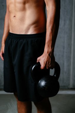 Atletik gövde ve kettlebell tutan el