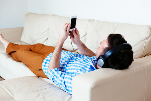 Man lying on sofa and listening to music