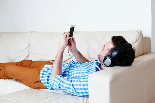 Hombre acostado en el sofá y escuchando música — Foto de Stock