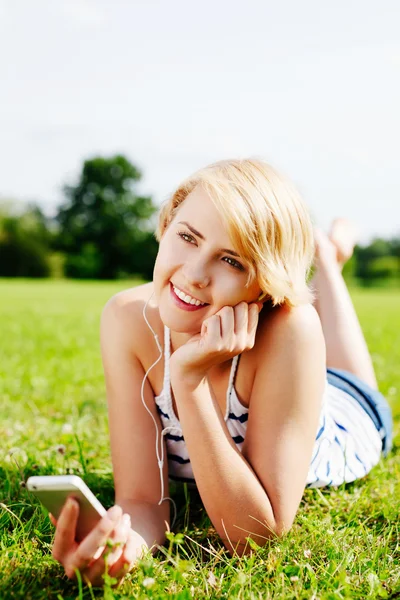 Frau im Gras hört Musik — Stockfoto