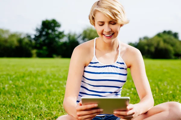 Vrouw op gras surfen digitale tablet — Stockfoto