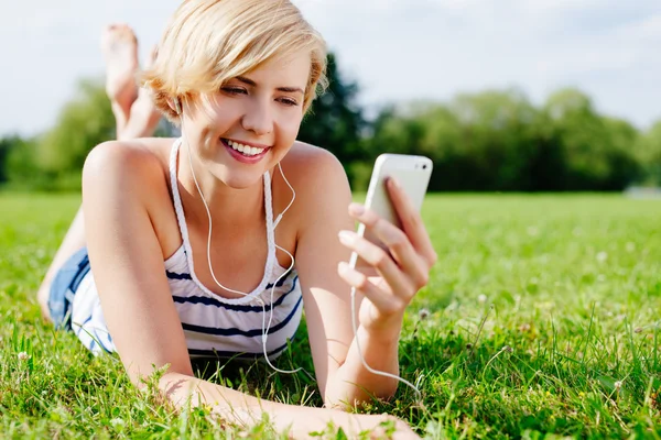 Женщина на траве слушает музыку — стоковое фото