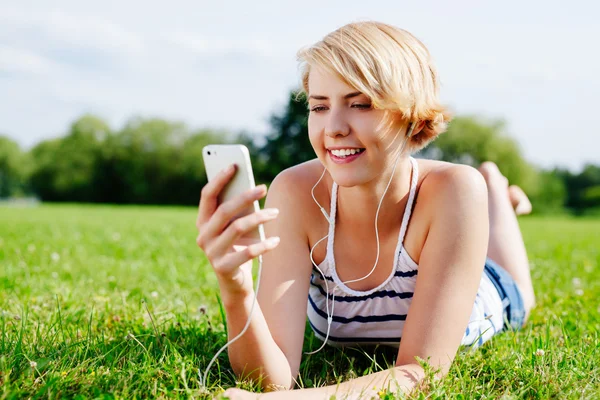 Mujer en la hierba escuchando música — Foto de Stock