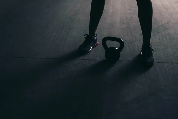 Pernas de um fisiculturista com um kettlebell — Fotografia de Stock