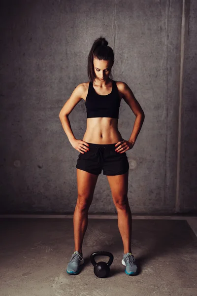 Female athlete looking at a kettlebell — Stock Photo, Image