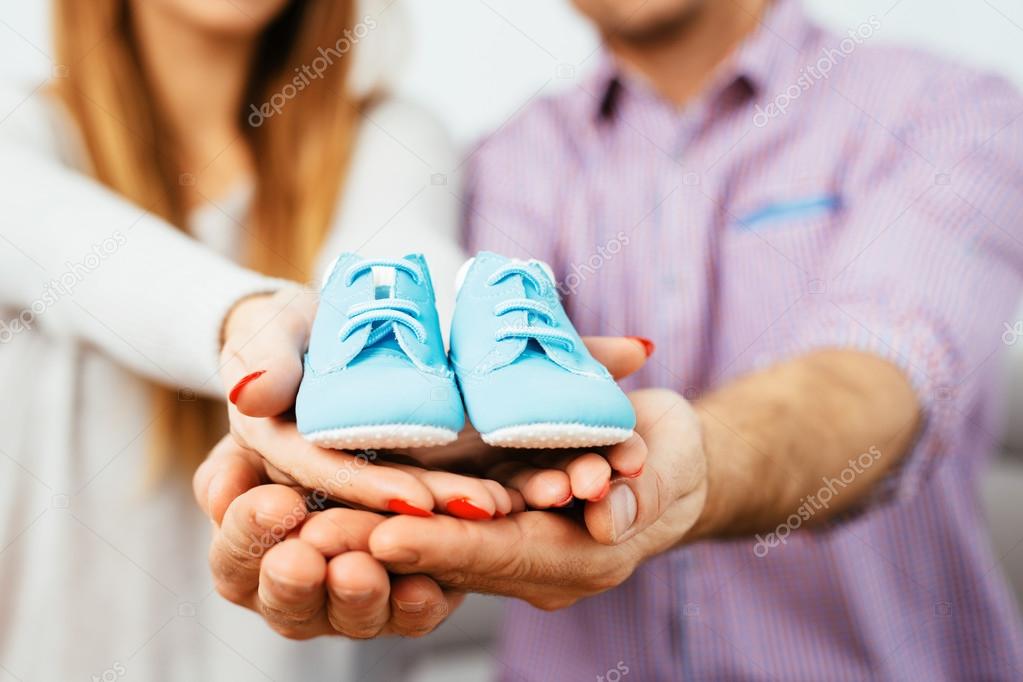 Prengant couple holding baby shoes