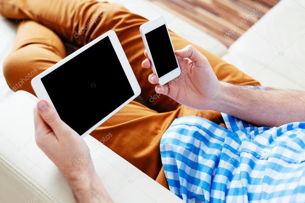 Man comparing tablet and smartphone