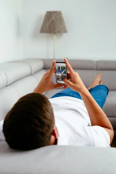 Mann benutzt Smrtphone auf Sofa — Stockfoto