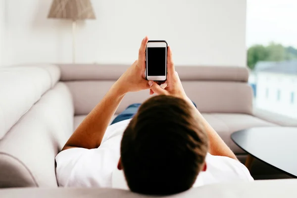 Man using smrtphone on sofa — Stock Photo, Image