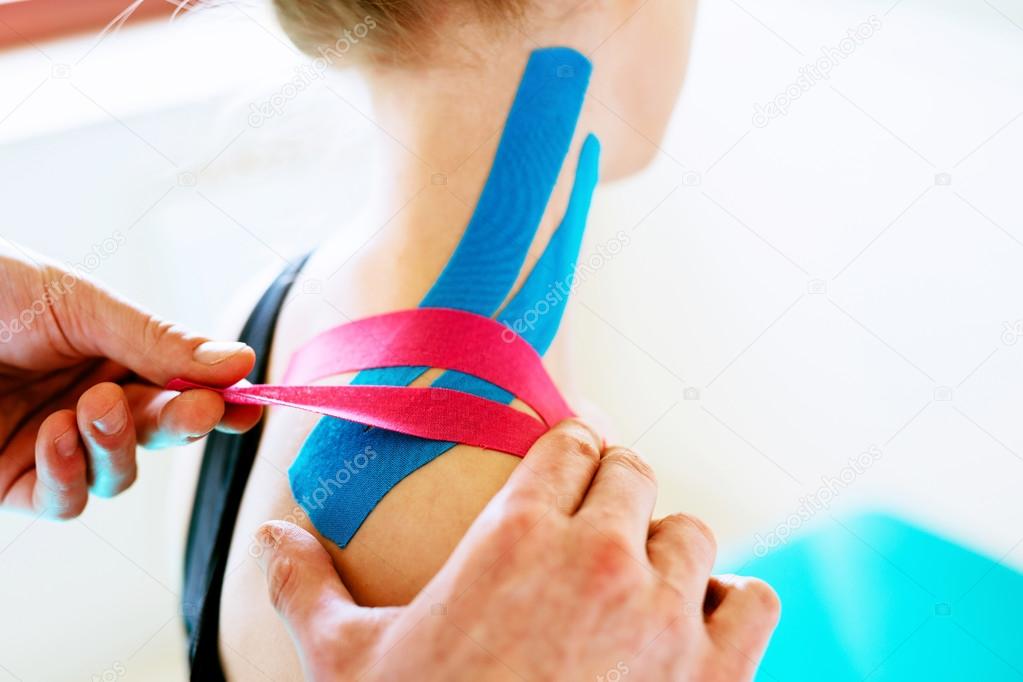 Therapist applying tape to patient shoulder