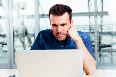 Genç adam bir dizüstü bilgisayar ekranına bakarak