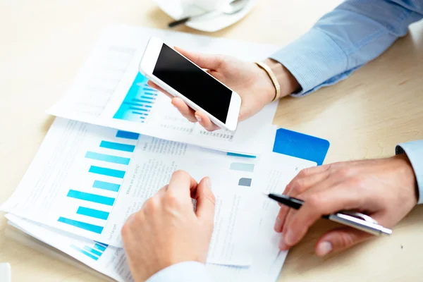 Documents and hands holding a smartphone — Stock Photo, Image