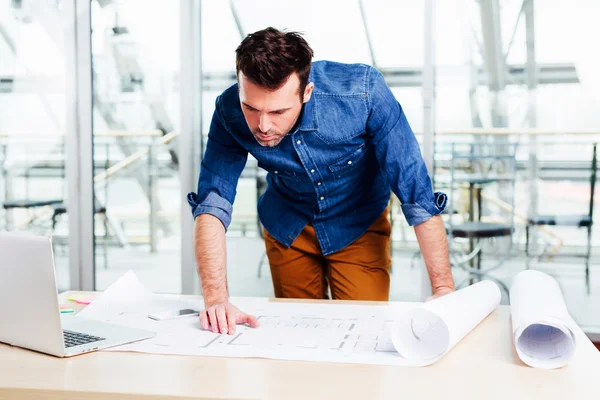 Jovem arquiteto olhando atentamente para um design — Fotografia de Stock