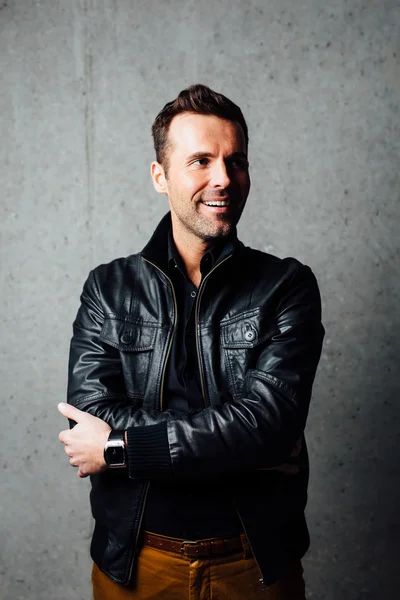 Happy man in leather jacket against concrete wall — Stock Photo, Image