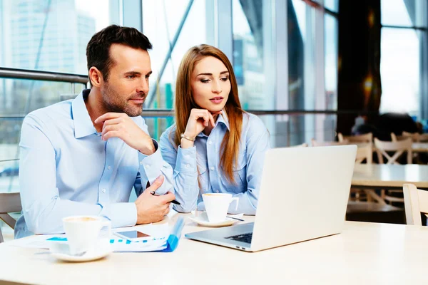 Young busy professionals looking at a laptop