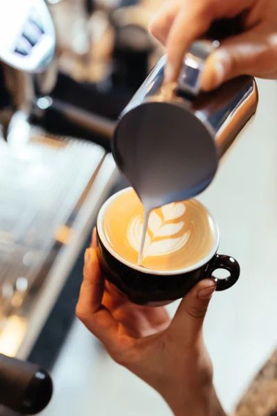 Barista menuangkan susu ke dalam cappuccino seni — Stok Foto