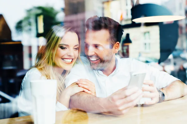 Casal olhando para smartphone na cafetaria — Fotografia de Stock