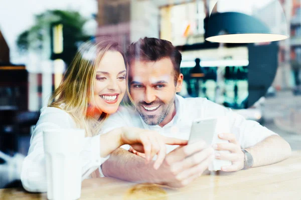 Glückliches Paar schaut im Café aufs Smartphone — Stockfoto