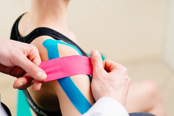 Physiotherapeut klebt Klebeband an Patient — Stockfoto