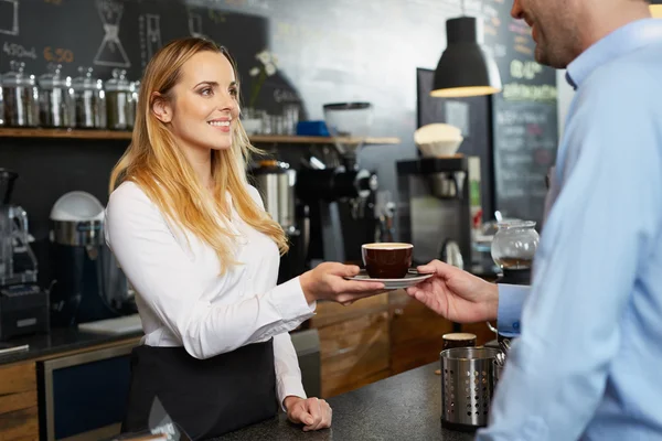 Női barista kínál egy cappuccino csésze — Stock Fotó