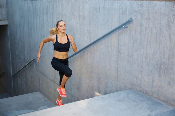 Athletic woman running up stairs