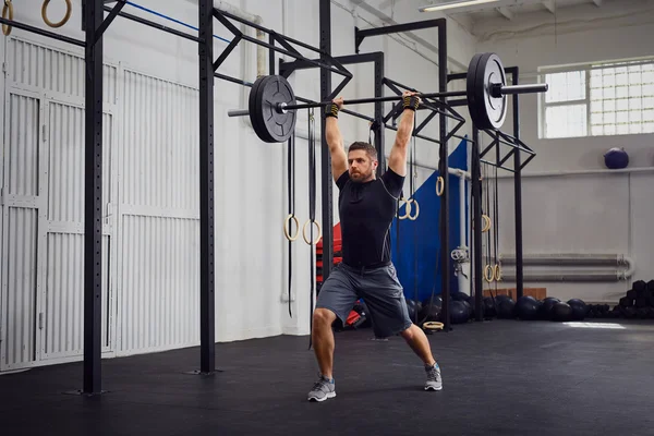 Lunges with barbells over head — Stock Photo, Image