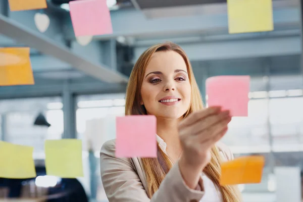 Business woman sticking notes on window — стоковое фото