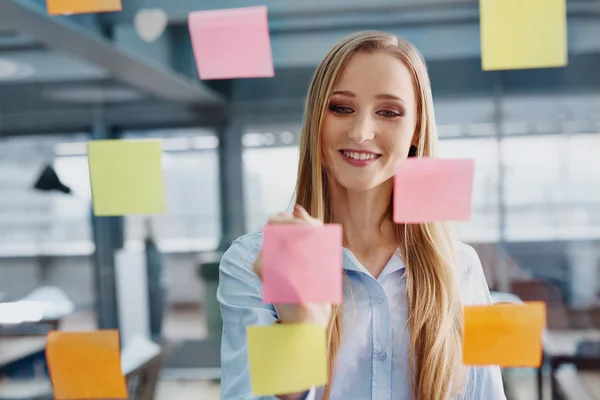 Businesswoman sticking notes on window — Stock Photo, Image