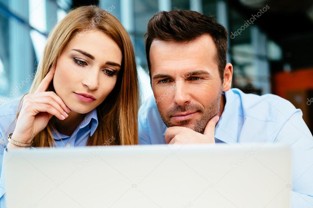 Two managers looking closely at a laptop screen