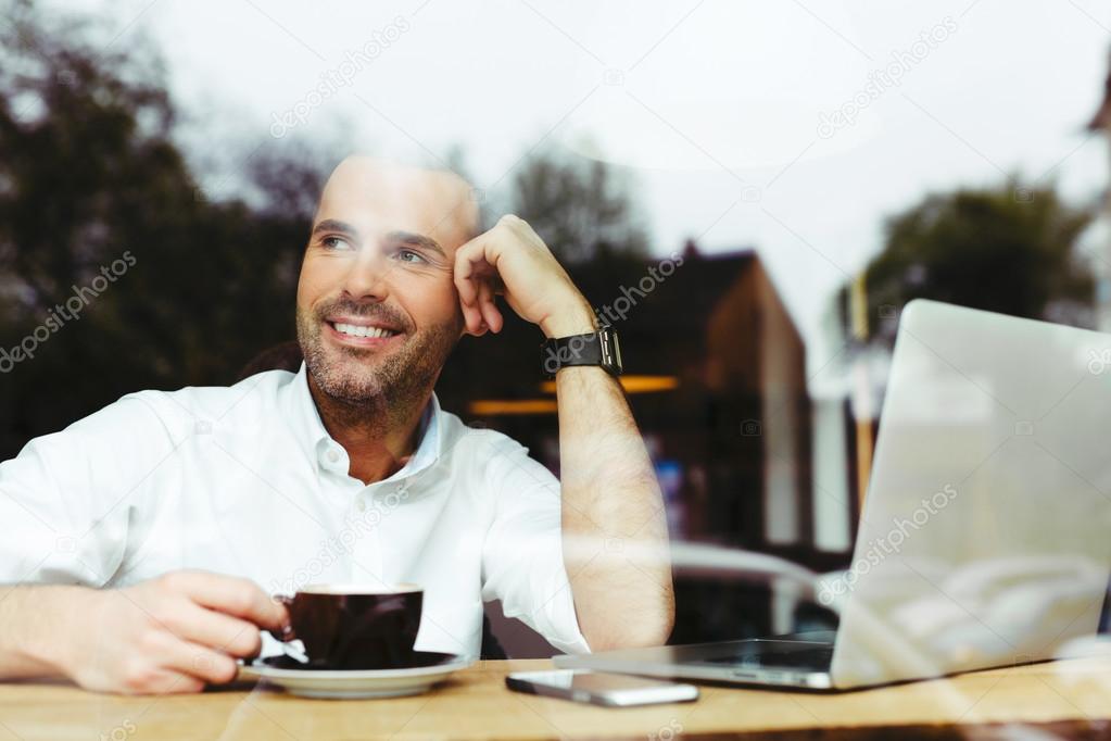 Happy young man drinking coffee at cafe
