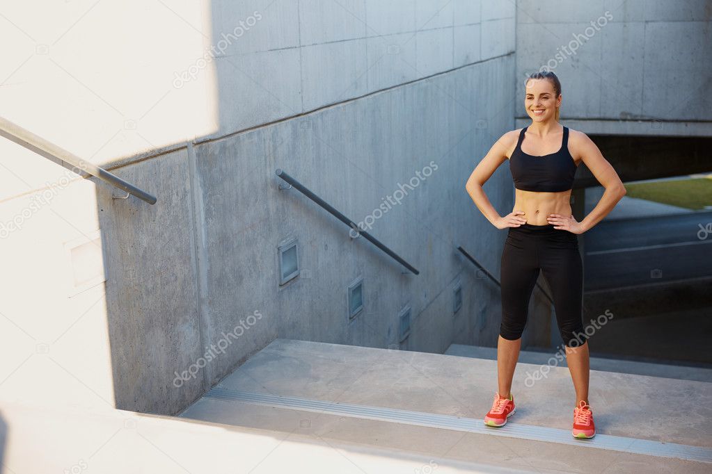 Happy female runner standing on stairs