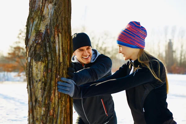 Paar dehnt sich im Winter vor dem Laufen — Stockfoto