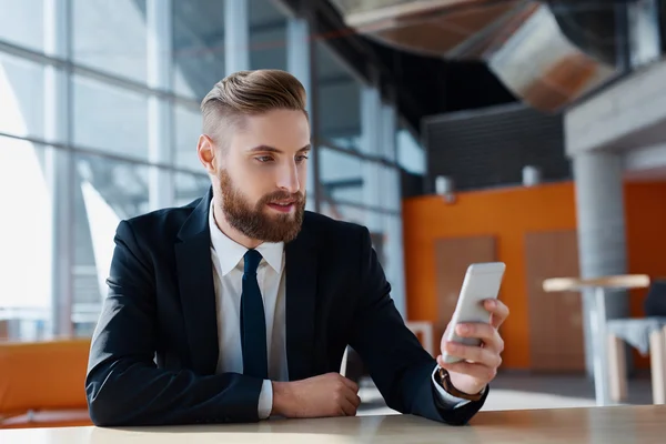 Hipster met pak bladeren zijn smartphone — Stockfoto