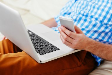 cep telefonu ve dizüstü bilgisayar tutan kişi