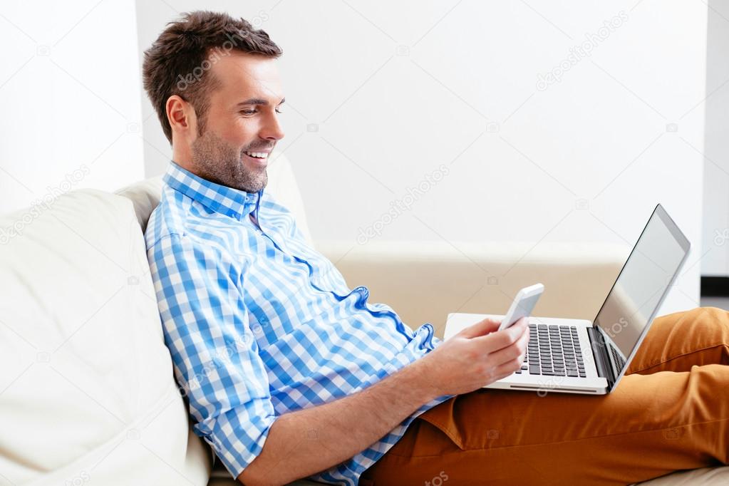 man using his mobile and a laptop