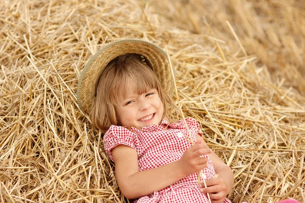 Uma menina deitada no feno — Fotografia de Stock