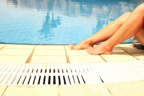 Piernas femeninas en el agua de la piscina — Foto de Stock