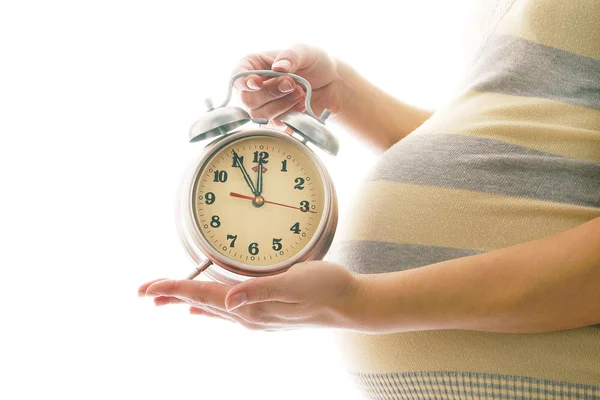 Young pregnant woman with alarm clock — Stock Photo, Image