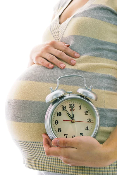 Молодая беременная женщина с будильником — стоковое фото