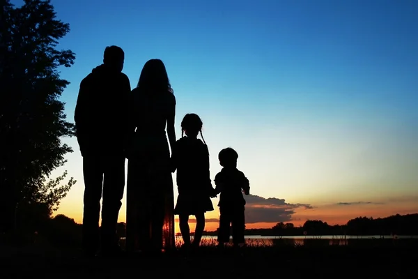 Baba, anne ve iki çocuğu siluetleri — Stok fotoğraf